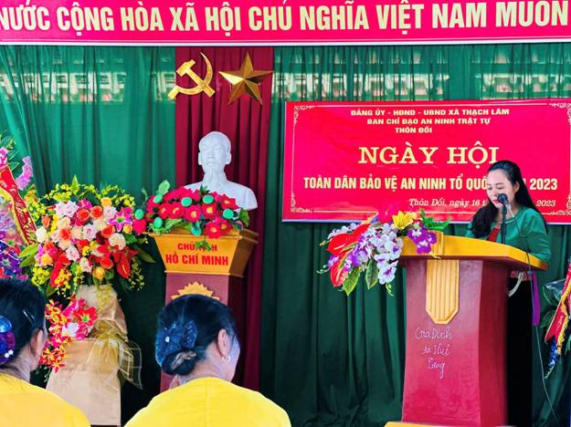 A person standing at a podium with flowers and a red banner

Description automatically generated