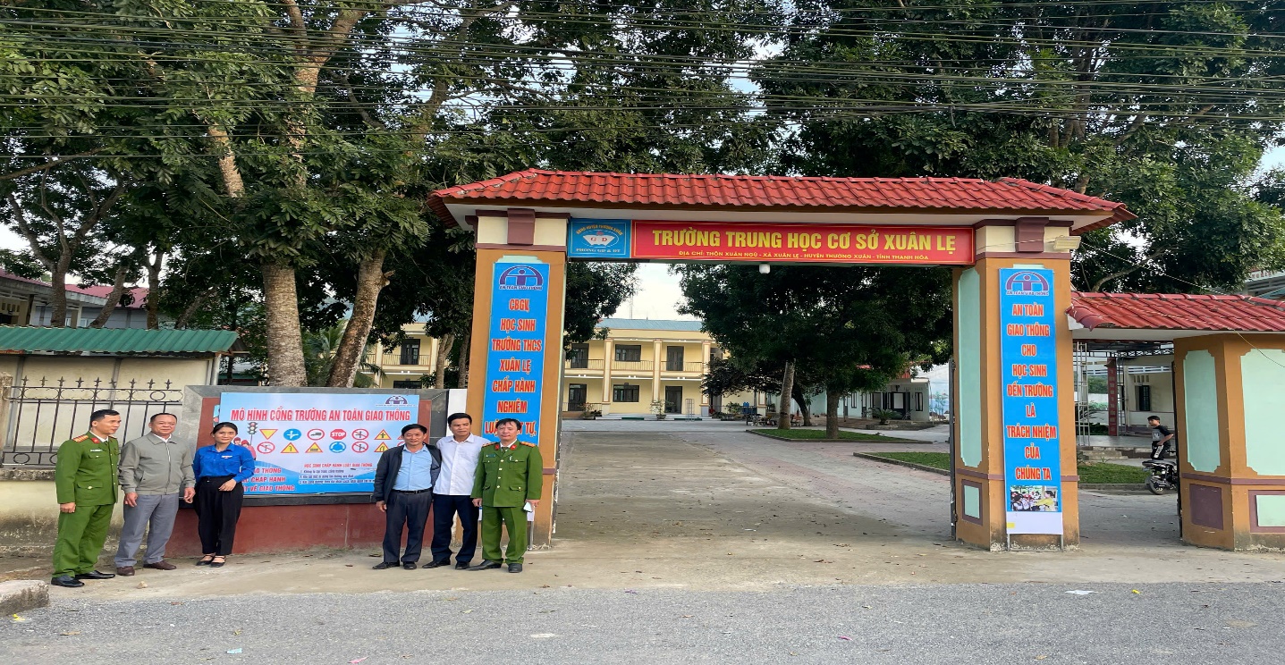 A group of people standing in front of a sign
Description automatically generated