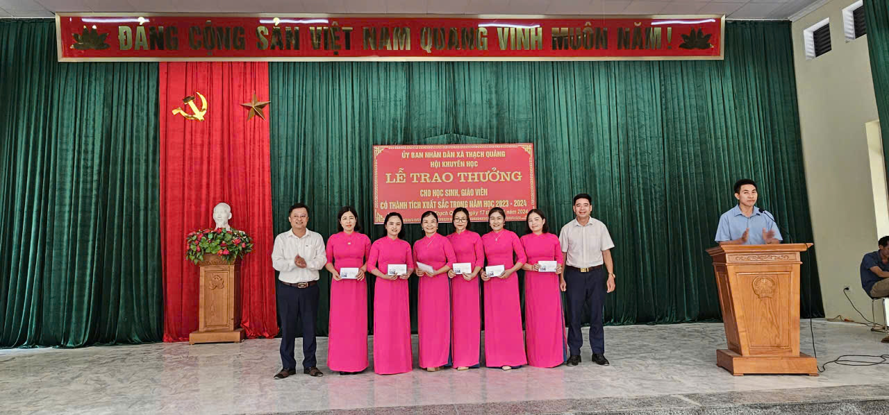 A group of people standing in front of a sign
Description automatically generated