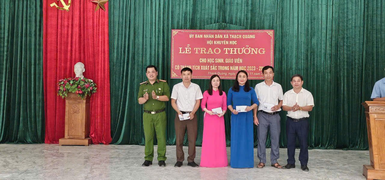 A group of people standing in front of a red sign
Description automatically generated