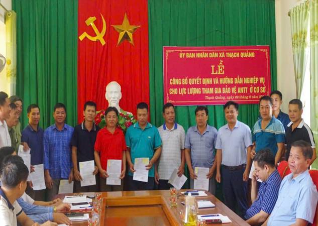 A group of people standing in front of a flag

Description automatically generated