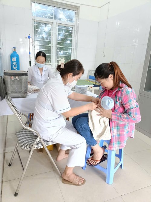 A nurse giving a baby a shot
Description automatically generated