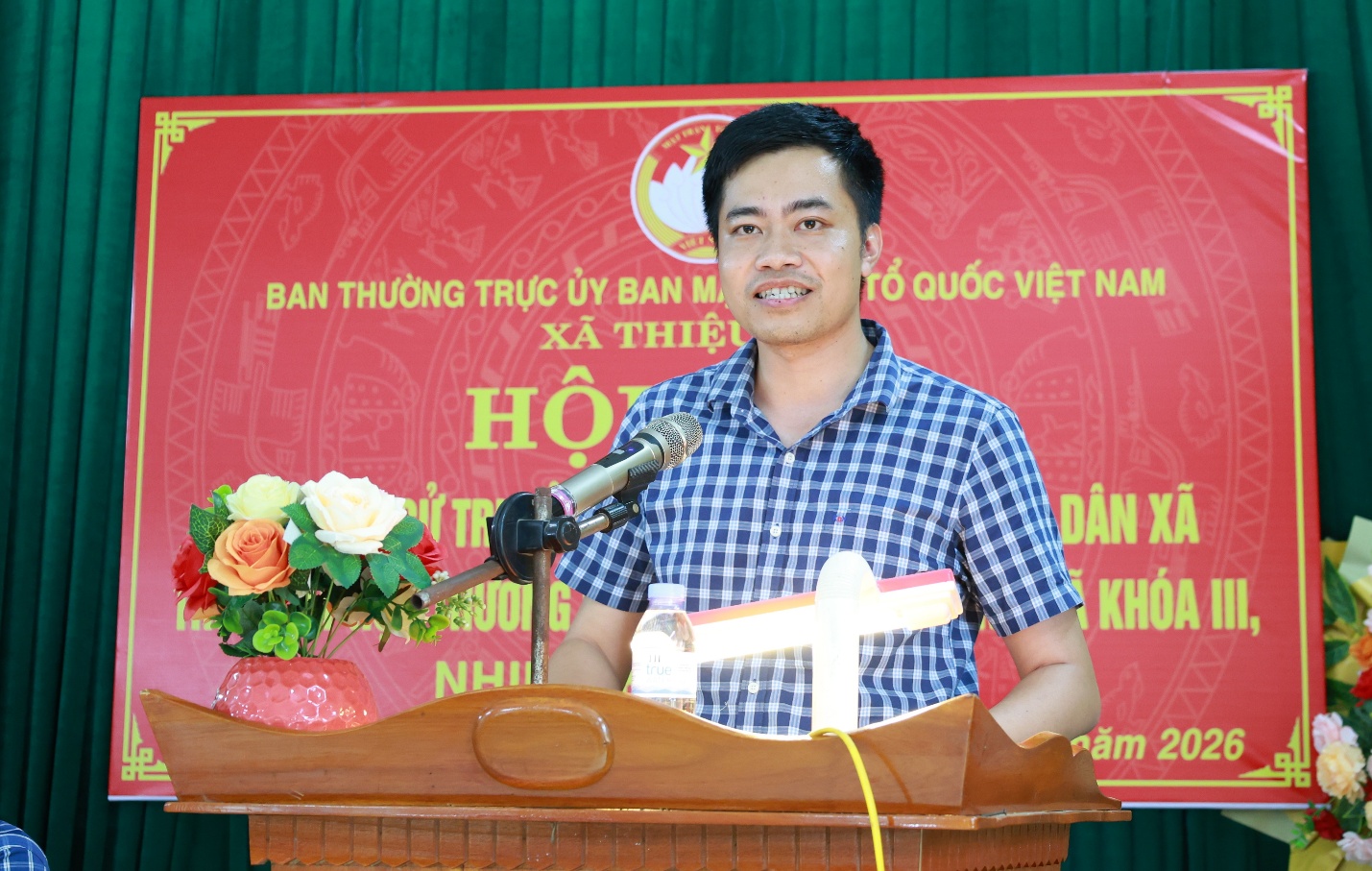 A person standing at a podium with a microphone
Description automatically generated
