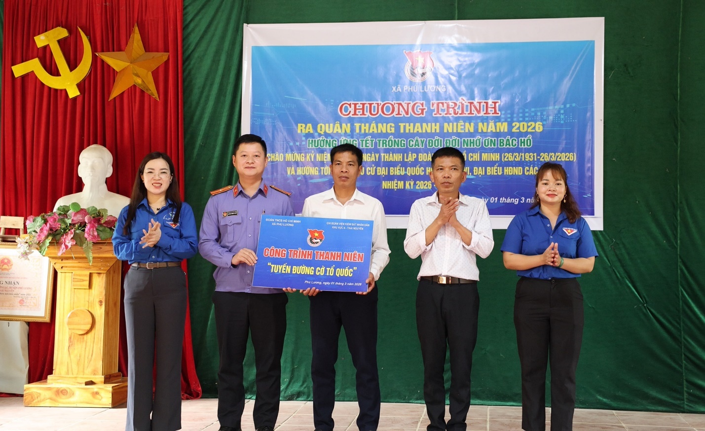 A group of people standing in front of a banner
Description automatically generated