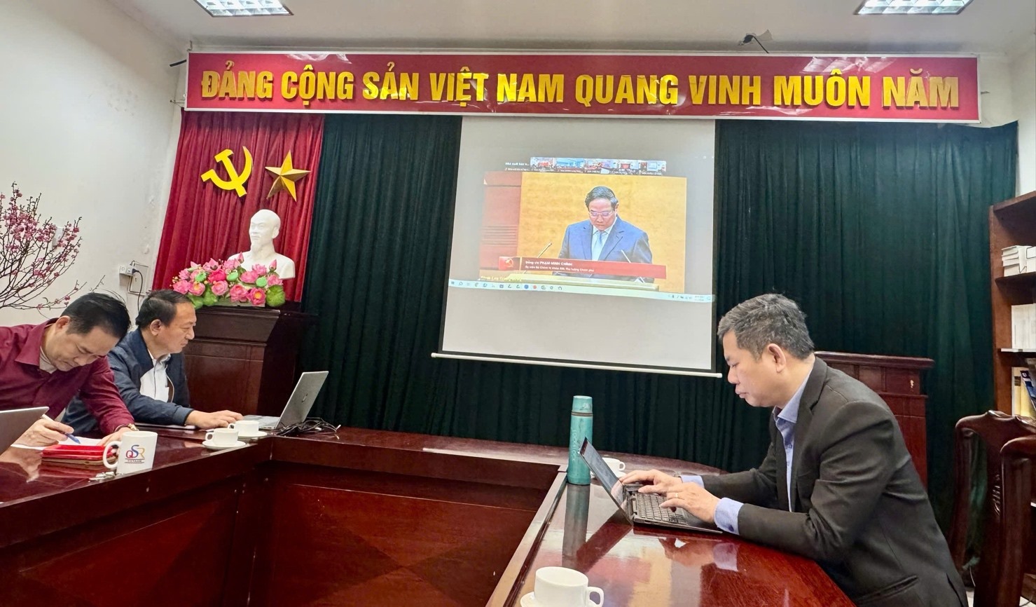 A group of people sitting at a table with a screen on it
AI-generated content may be incorrect.