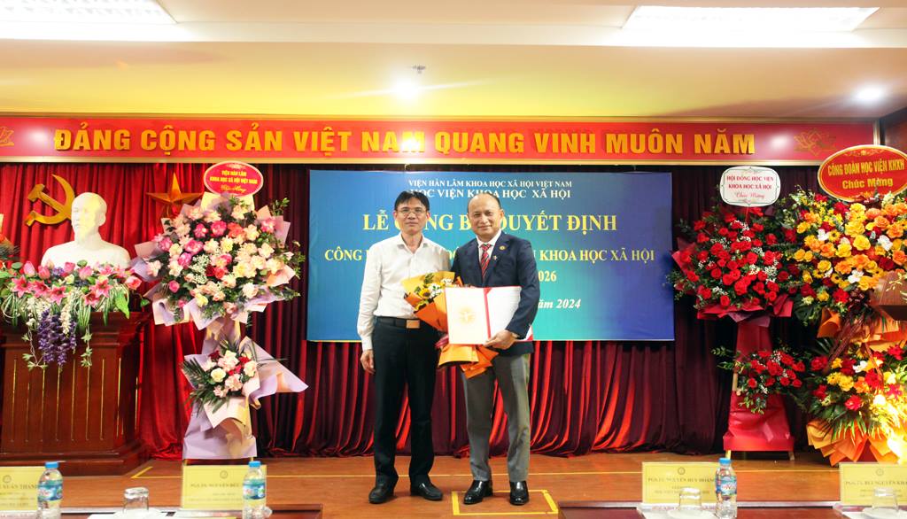 PGS.TS. Nguyễn Đức Minh - Phó Chủ tịch Viện Hàn lâm KHXH Việt Nam trao Quyết định và tặng hoa chúc mừng đồng chí tân Giám đốc Học viện Nguyễn Huy Hoàng..